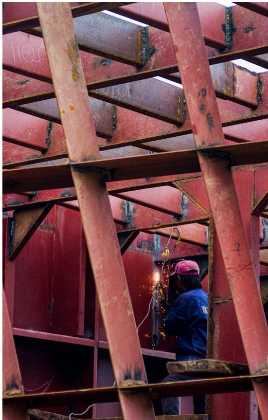 hombre soldando vigas de un estadio
